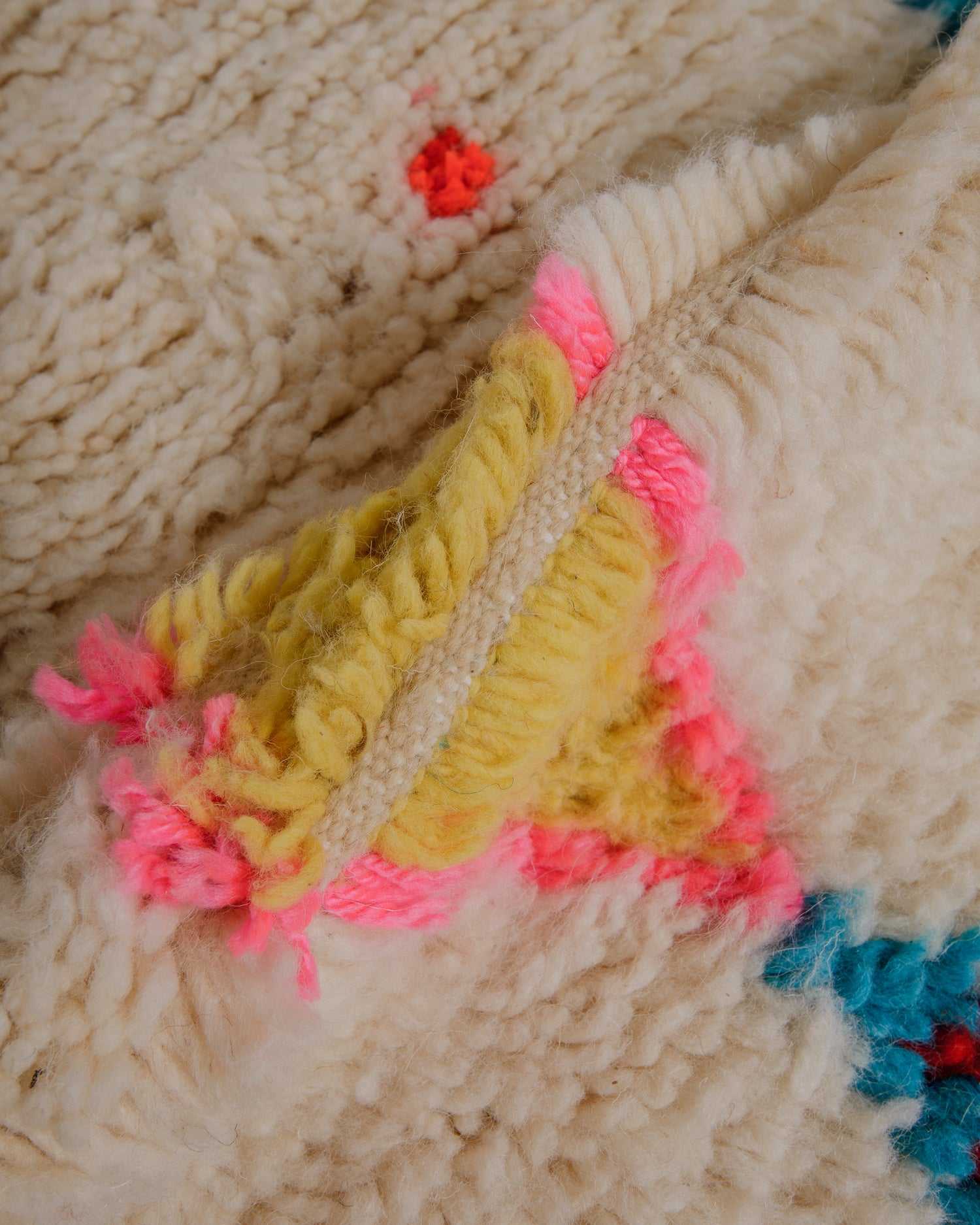 Close up of fluffy wool azilal rug with yellow and pink elements.