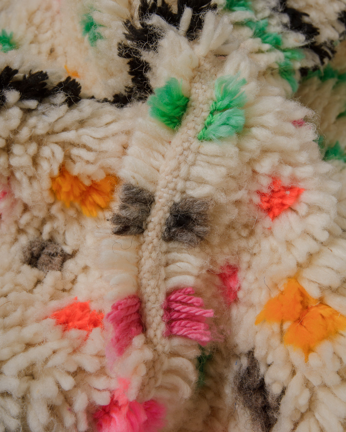 Close-up of a textured rug with colourful yarn accents.