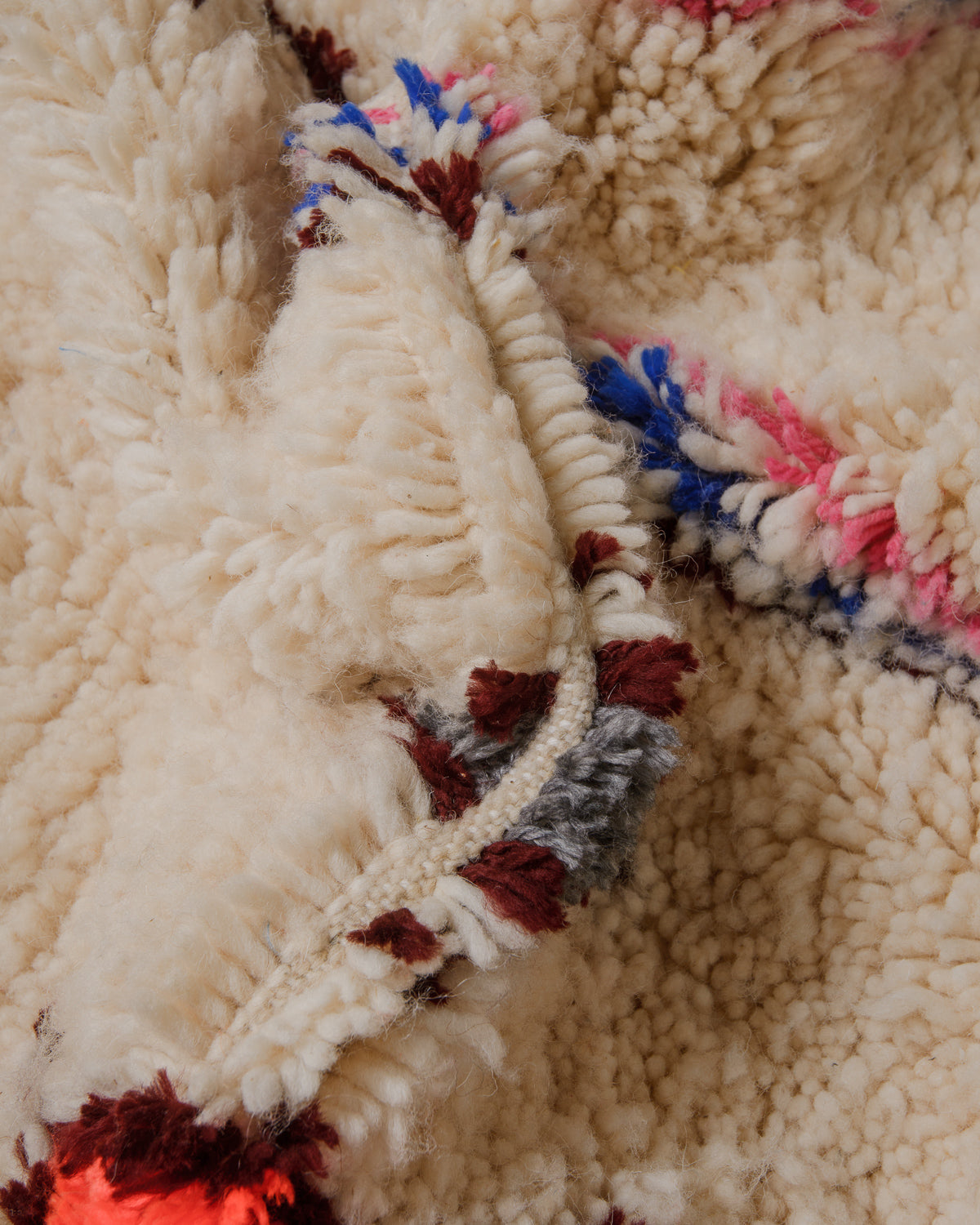 Close up of cream wool azilal with burgundy and grey details and a fluffy texture. 