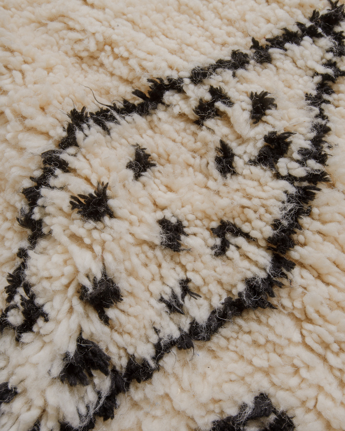 Close-up of a textured cream and black patterned rug.