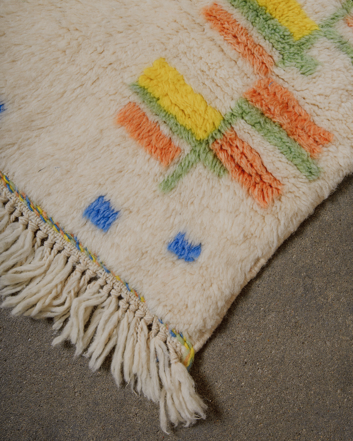 Close-up of a textured rug with colorful geometric patterns on a neutral background