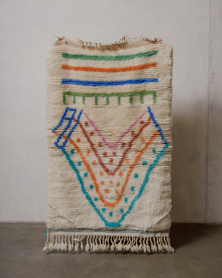 Handmade rug with colorful geometric pattern on a plain background