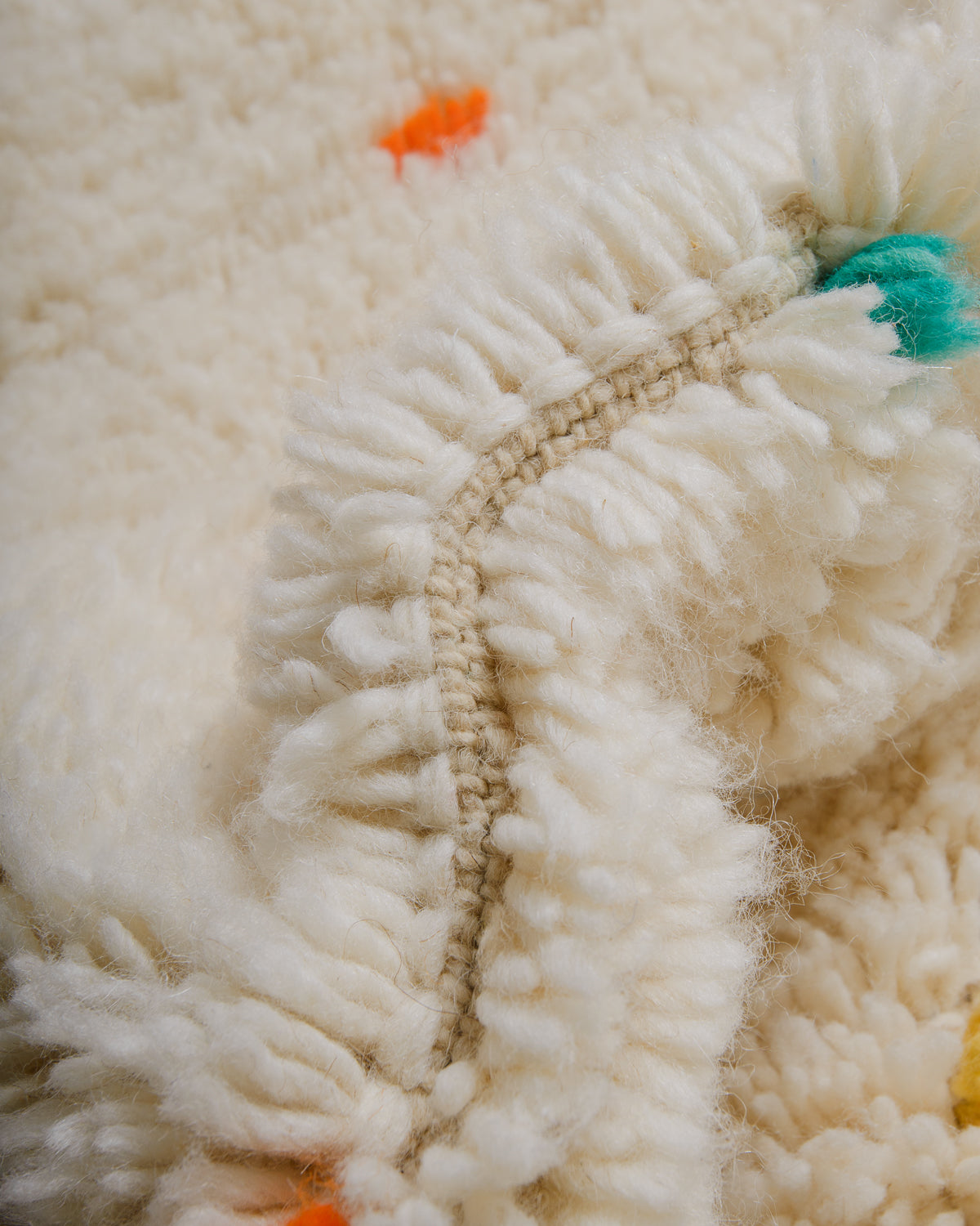 Detail of cream wool rug showing the density of the wool and coloured strands that make up the polka dots. 