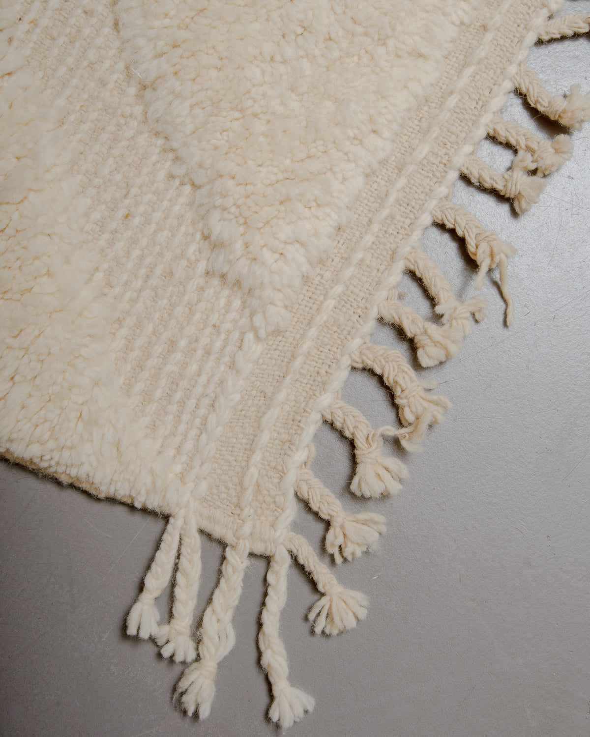 Corner of wool rug with natural tassels.
