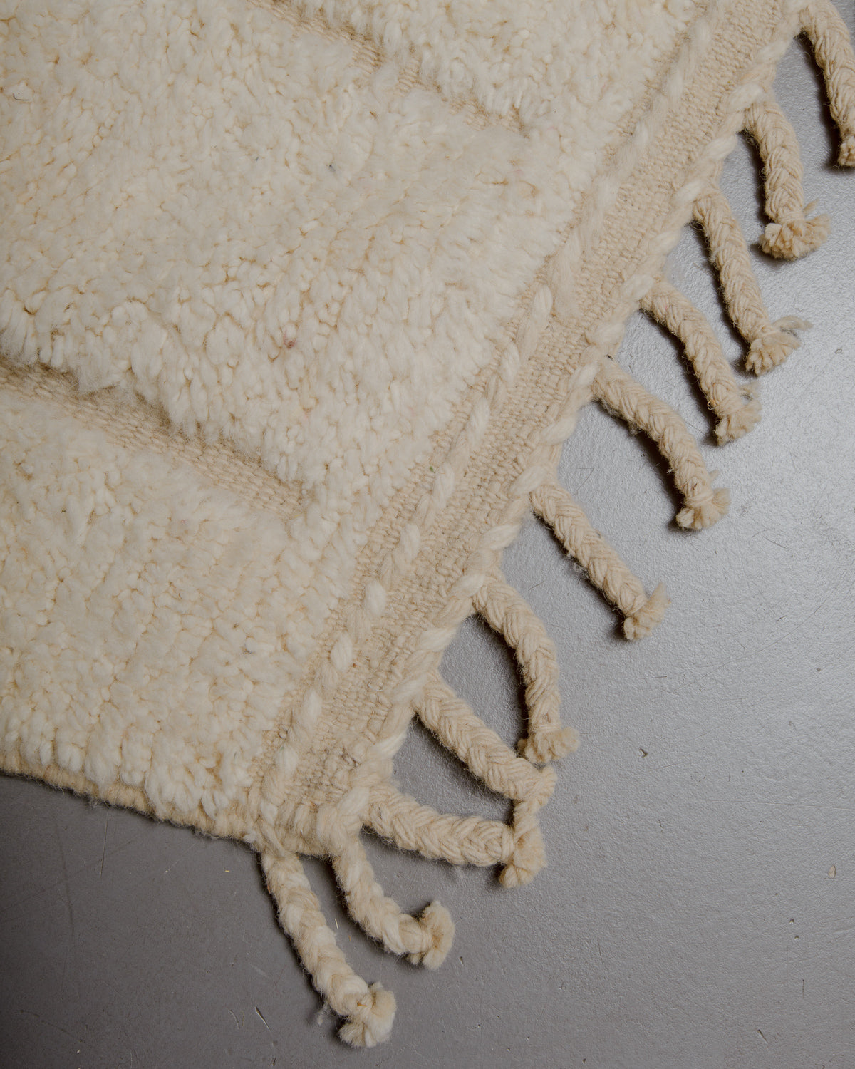 Corner of wool rug with natural tassels.