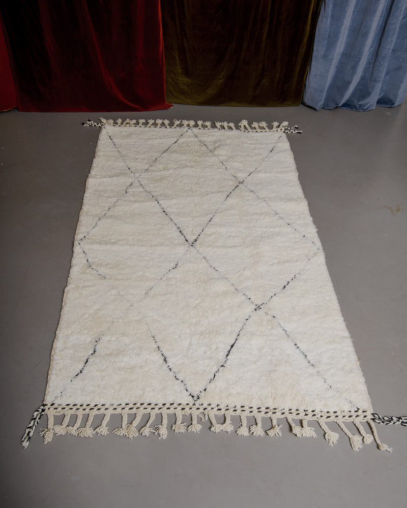 Berberlin Beniourain rug in cream and black wool on grey floor.