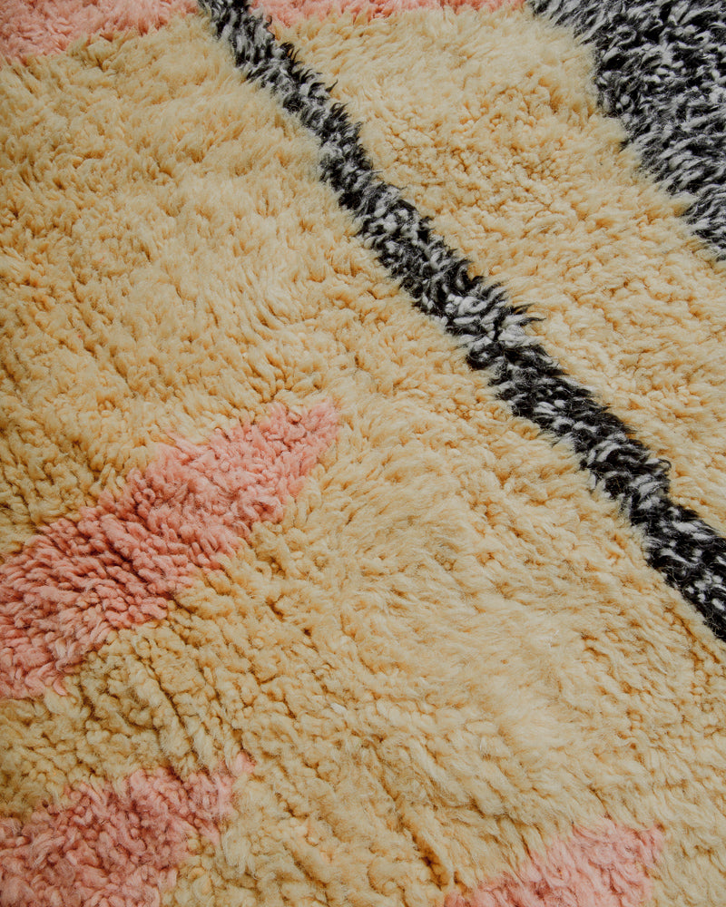 Surface of wool rug with rose, butter and black and white speckled wool.