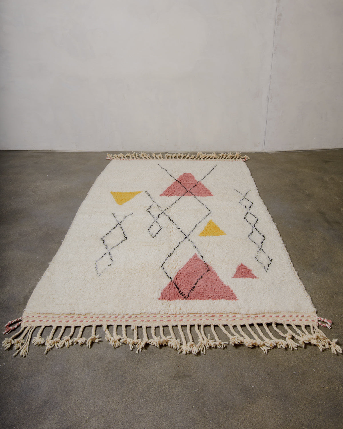 Cream rug with abstract geometric design  laying on concrete floor.