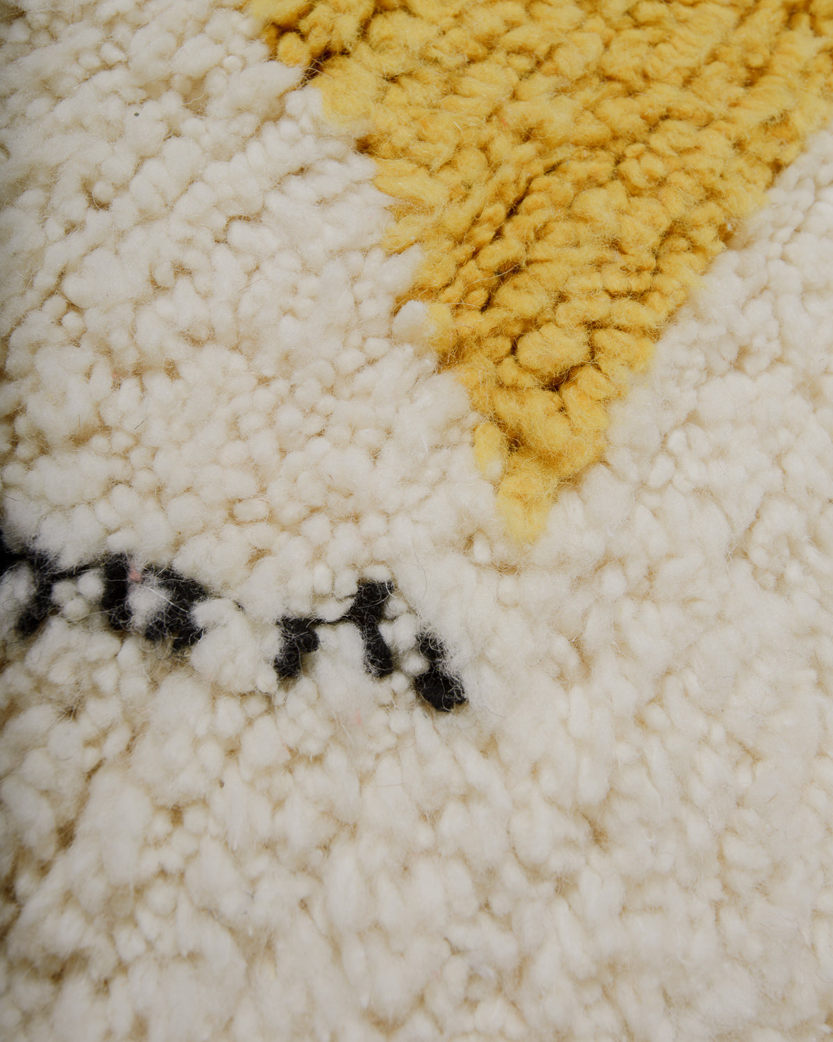 Close up of surface of wool rug with black, cream  and yellow. 