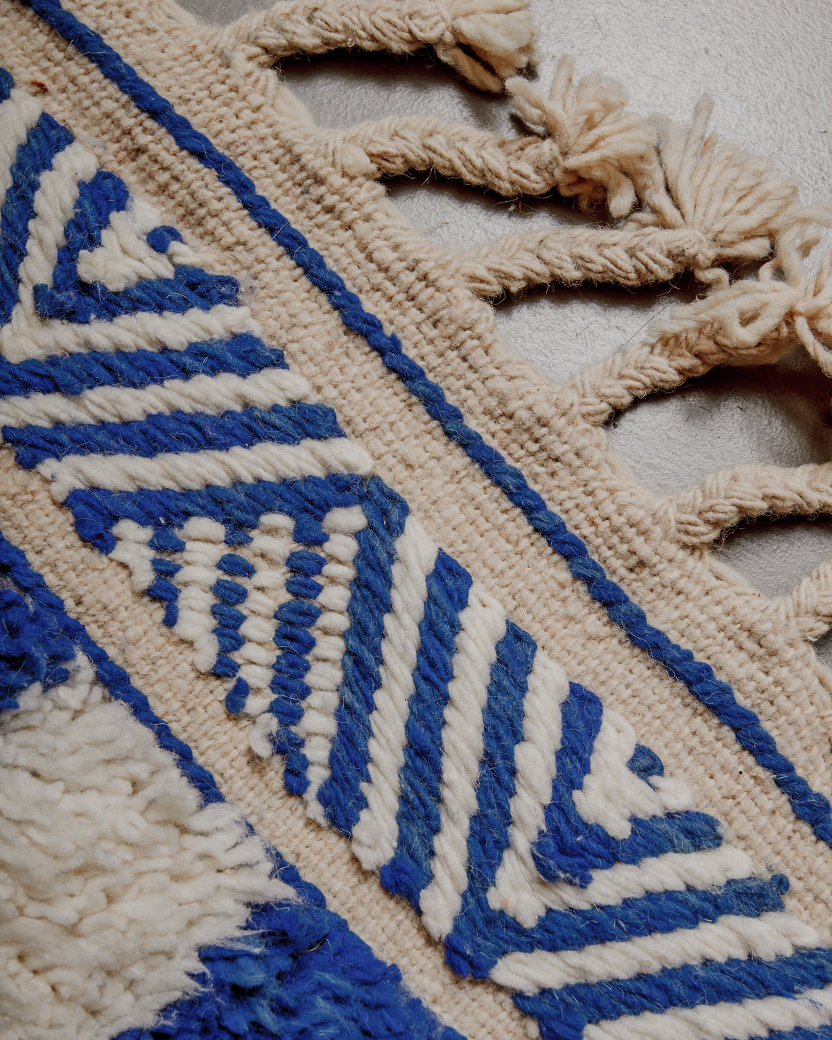 Edge of rug showing embroidered pattern and natural wool tassels. 