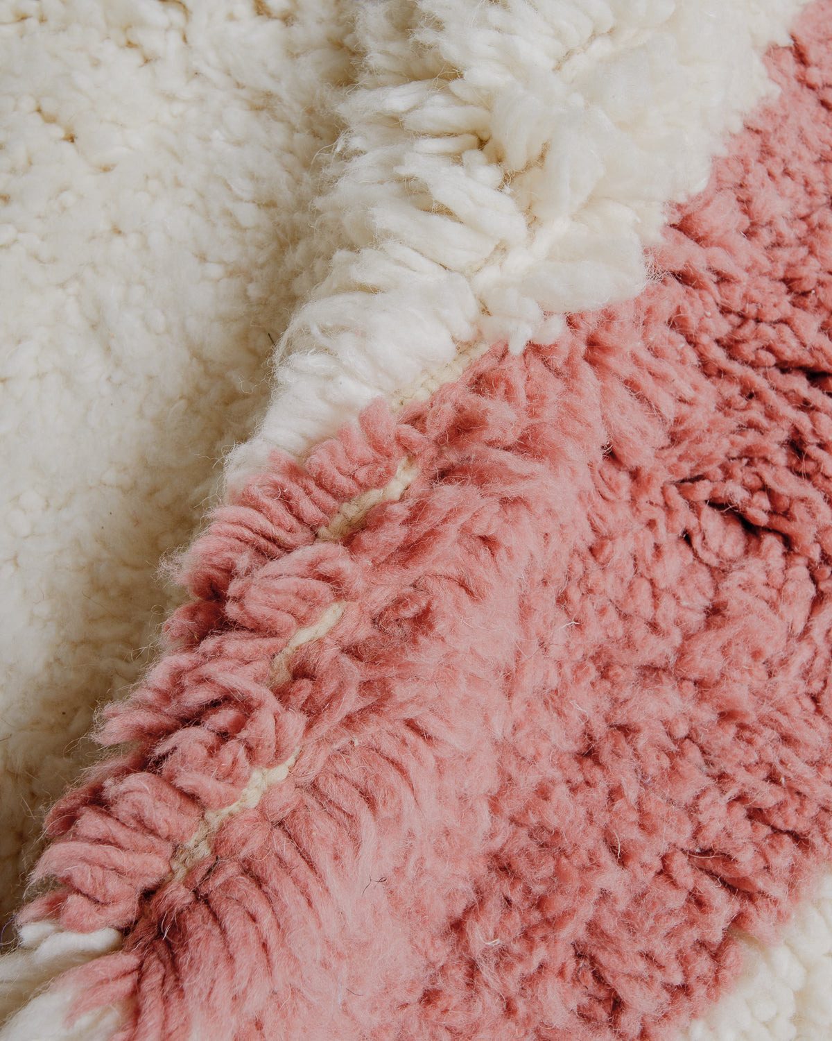 Close up showing cream and rose coloured wool with a soft, fluffy texture.