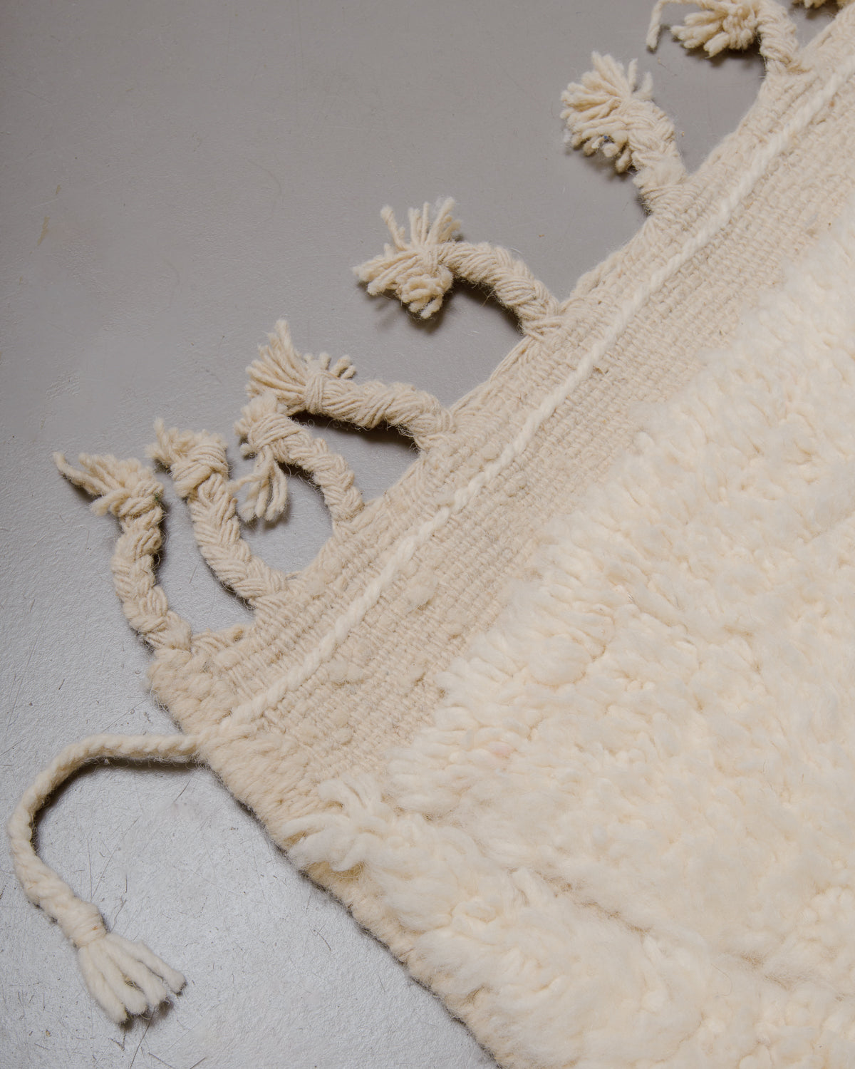 Corner of wool rug with natural tassels.
