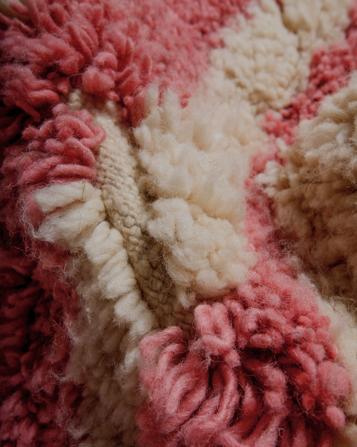 Close-up of a textured pink and cream wool rug surface
