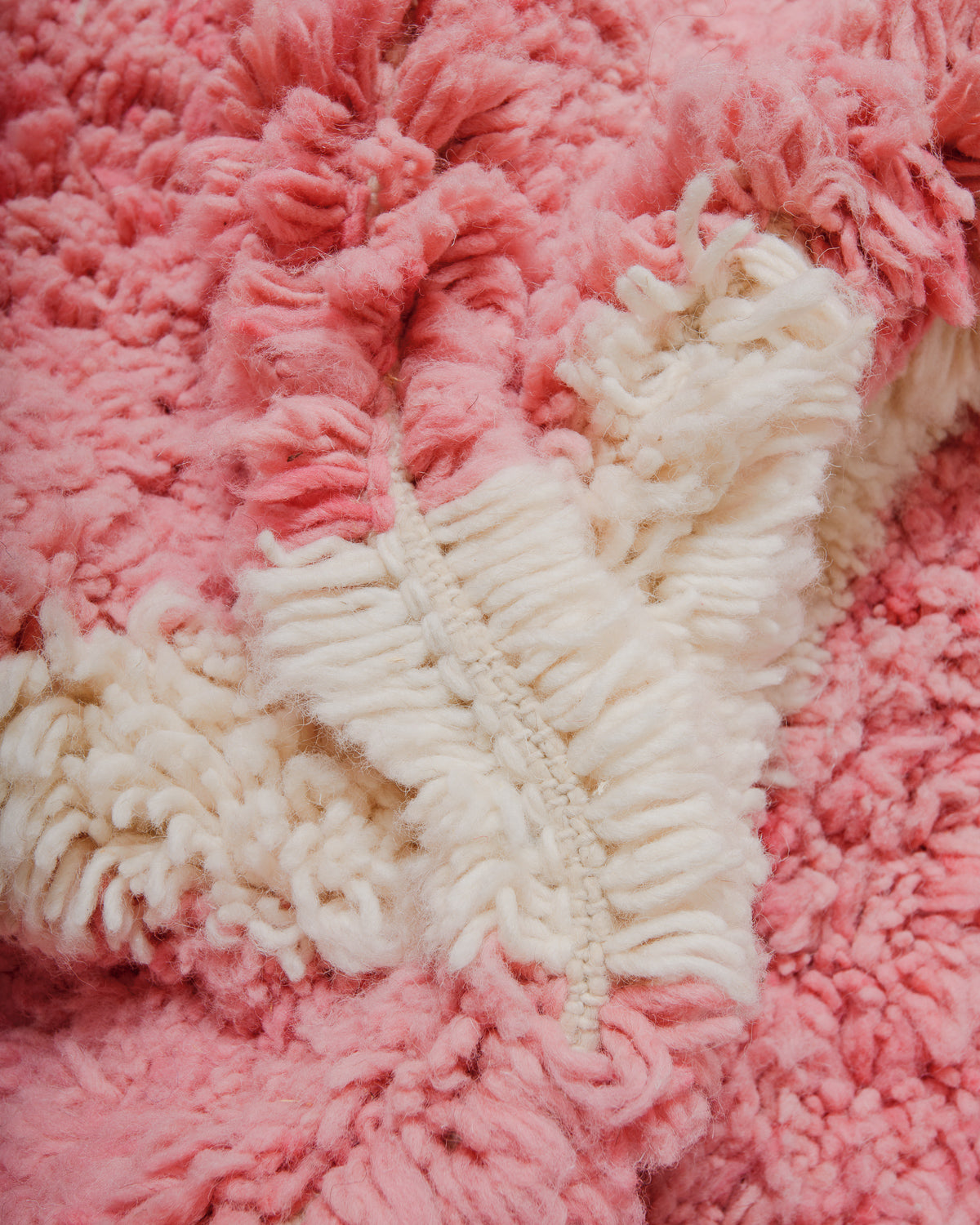 Close-up of a pink and cream wool rug showing the thick pile. 