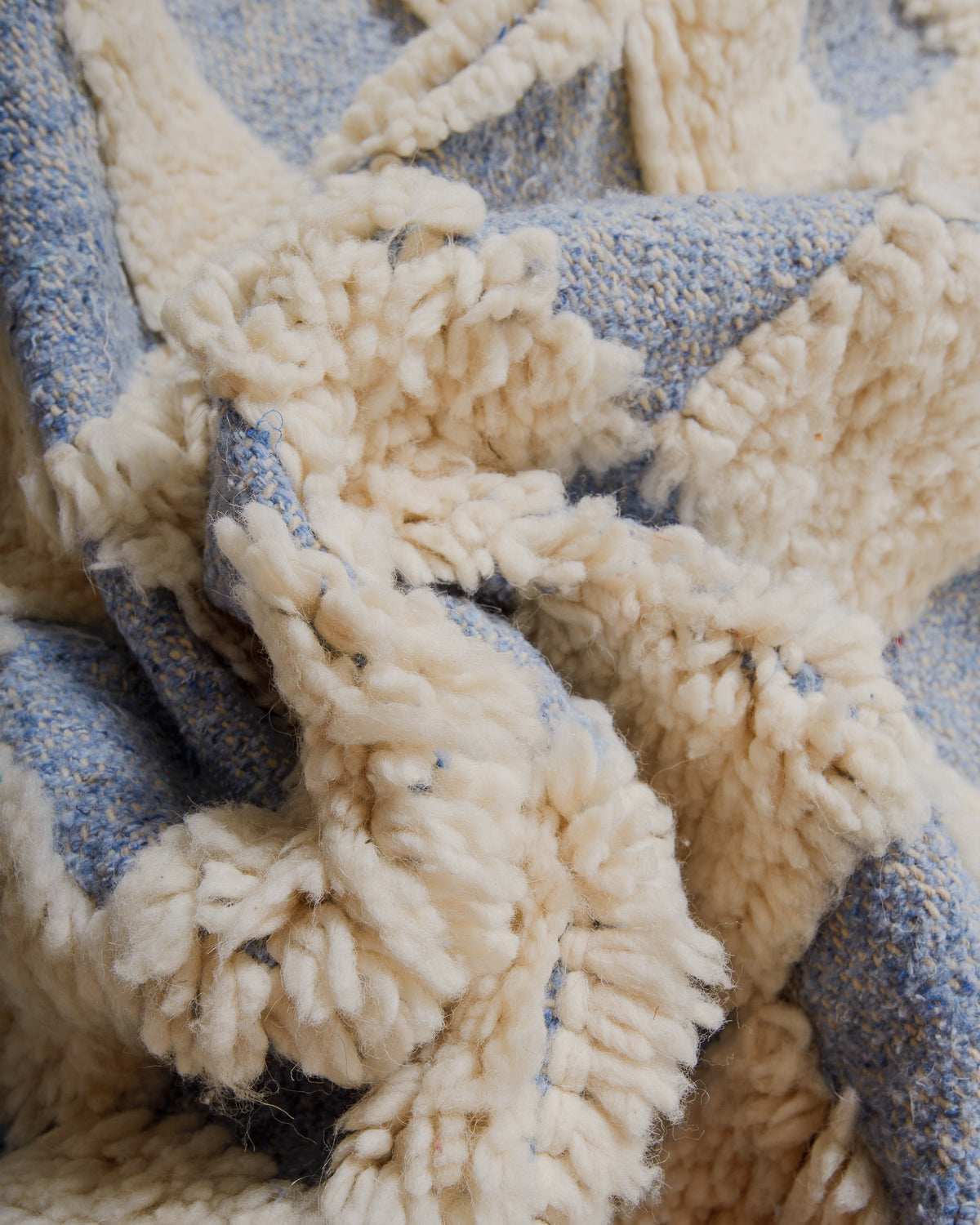 Close-up of a textured rug with blue and cream wool. 