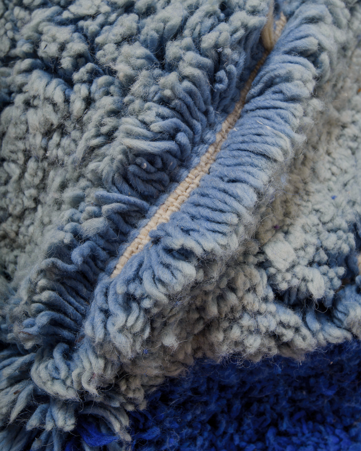 Close-up of a textured wool rug showing the thick pile and shades of blue.