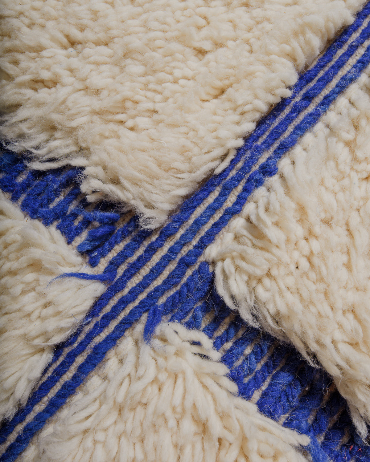Close-up of a textured rug with blue and cream wool.