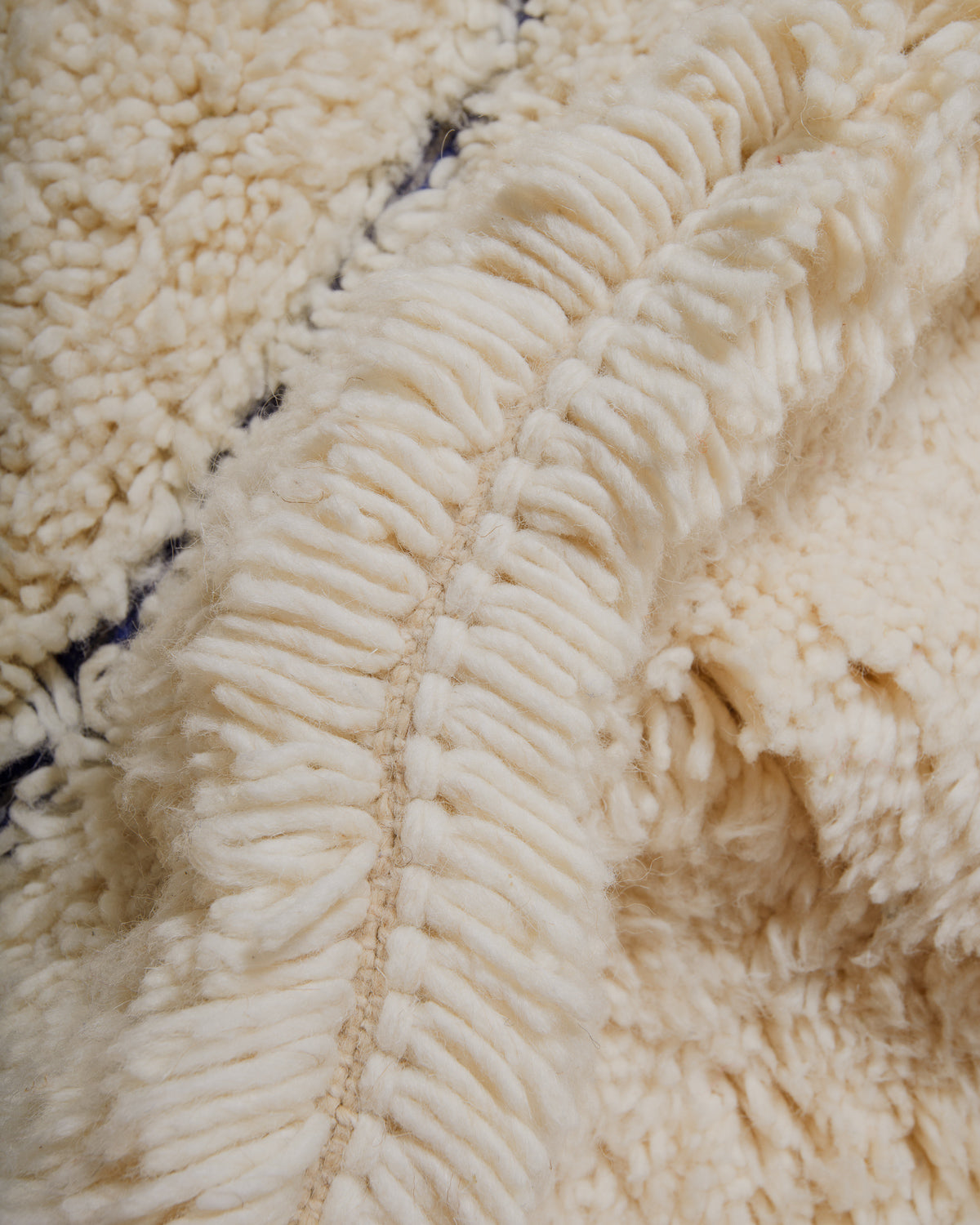 Close-up of a textured rug with blue and cream wool.