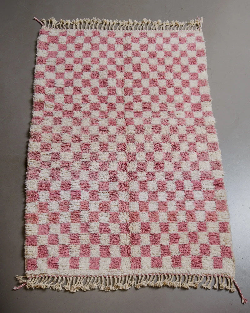 Pink checkered rug on grey floor. 