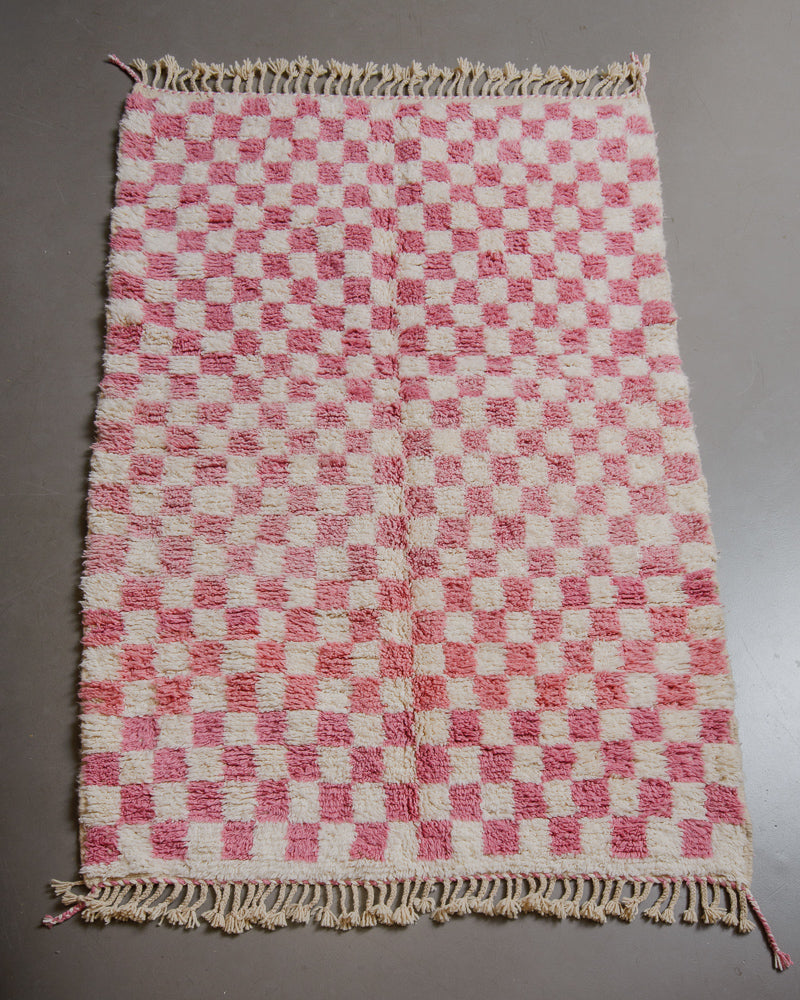 Pink checkered rug on grey floor. 