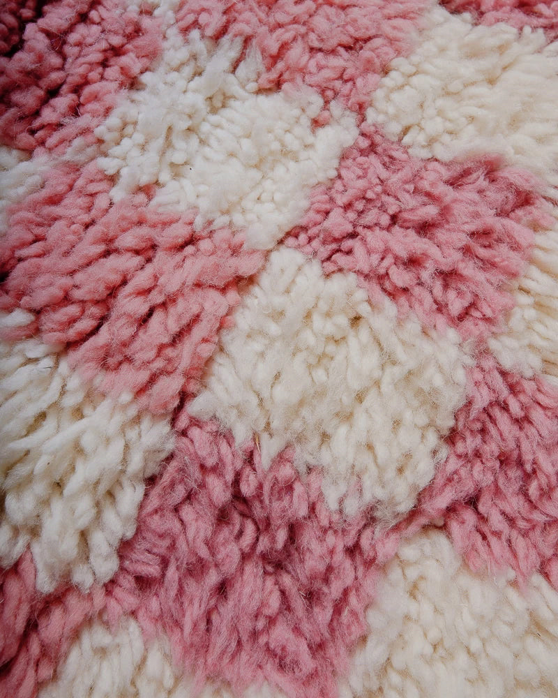 Surface of pink and cream checkered rug with two shades of pink.