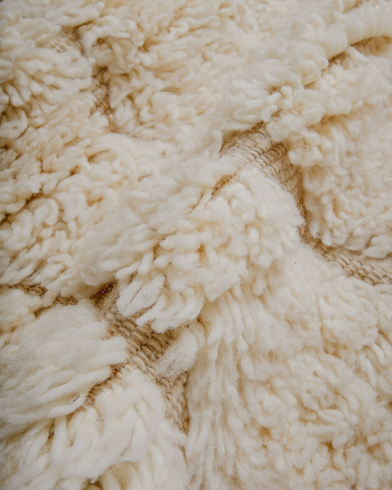 close up of cream wool rug with woven design and thick pile. 
