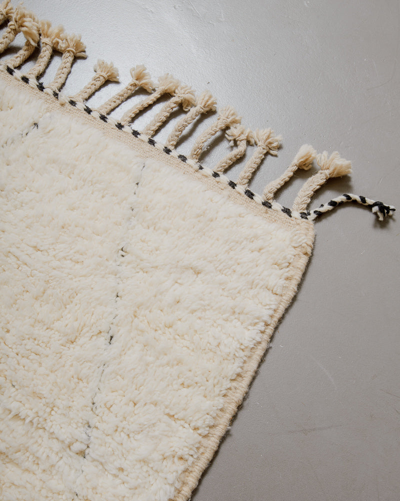 Corner of wool rug with natural tassels.