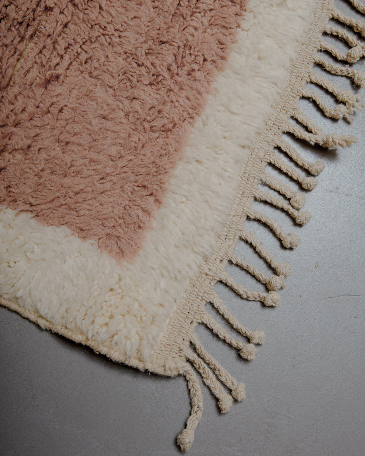 Corner of rug with natural wool tassels and tightly woven end.