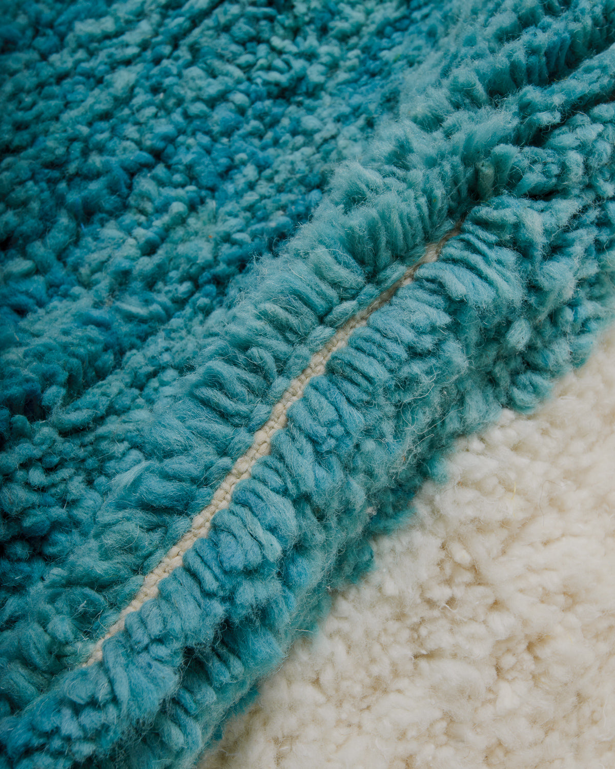 Close-up of a textured teal and cream rug.