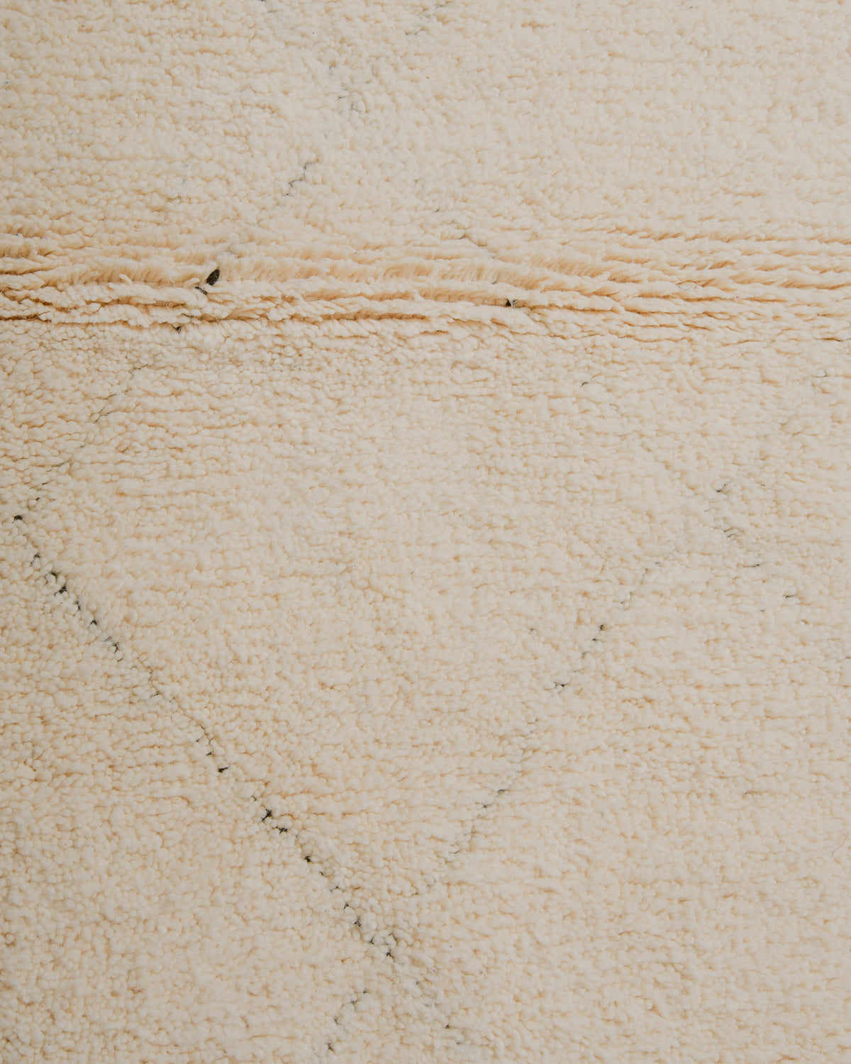 Surface of cream wool rug with subtle diamond pattern. 
