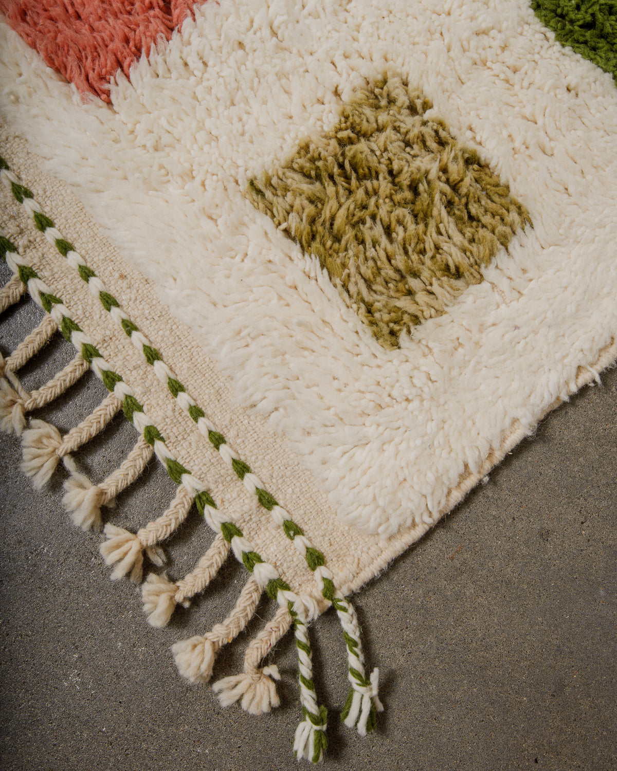 Cream rug with geometric pattern and natural tassels on a concrete floor