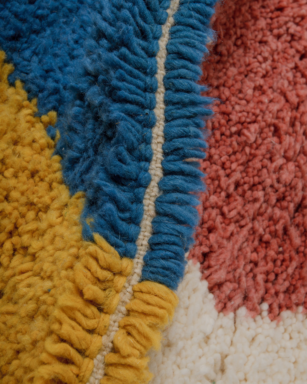 Close-up of a colorful textured rug with blue, yellow, and pink sections.