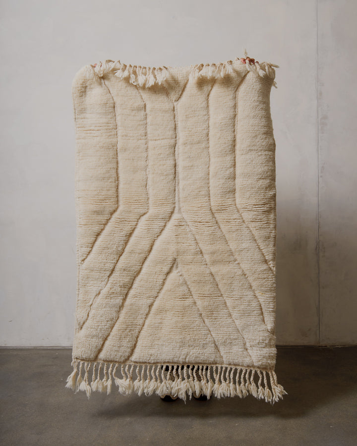 Cream textured rug with fringes on a plain background