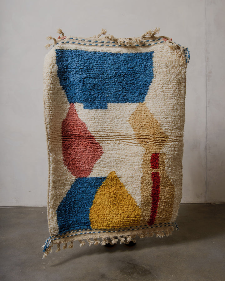 Multicolored geometric-patterned rug with tassels on a plain background