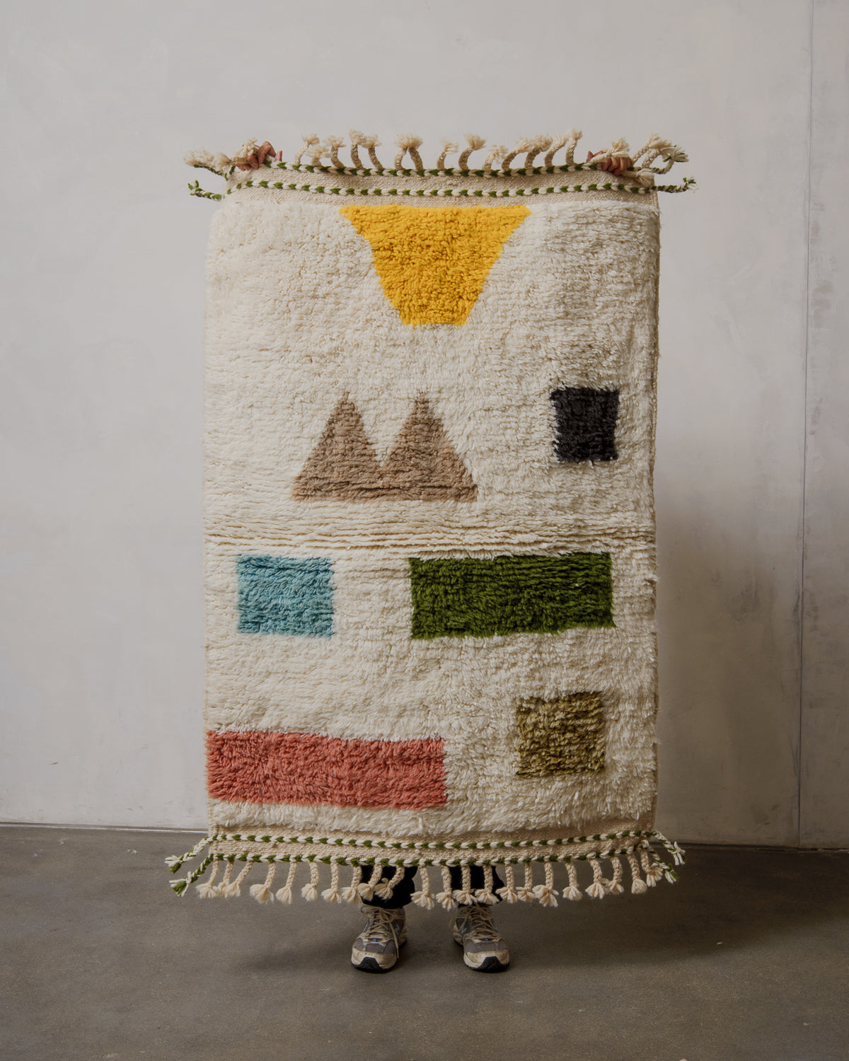 Handmade geometric rug with colorful shapes on a plain background