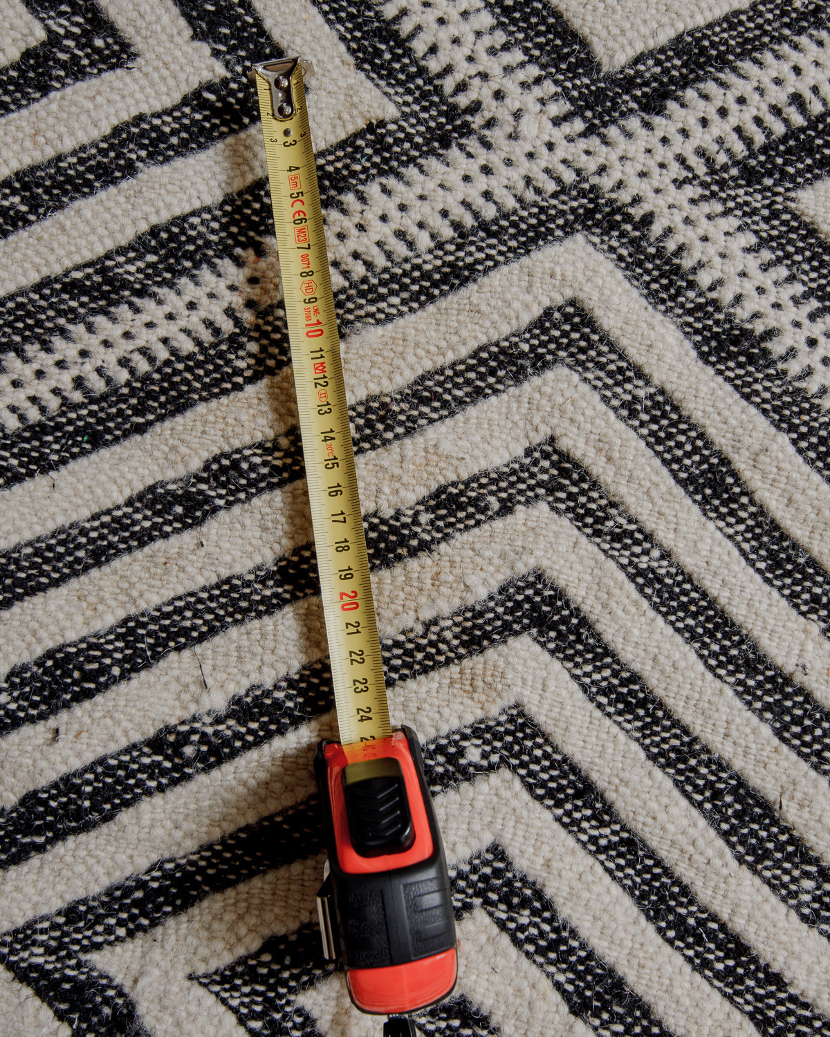Close up of surface of rug showing area of discolouration with tape measure showing 25cm.