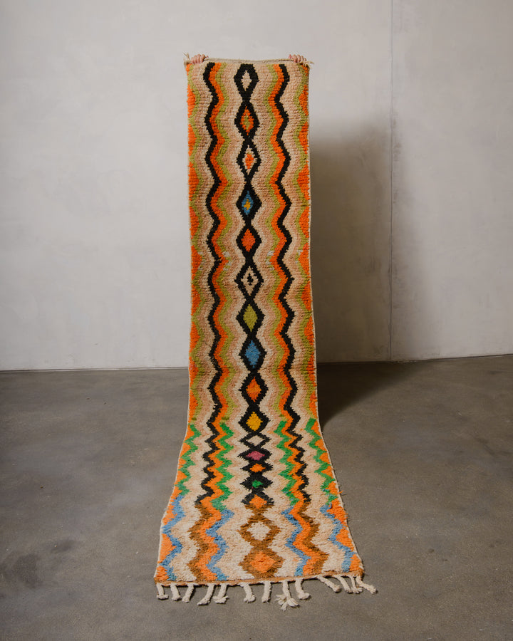 Colourful patterned Vintage runner rug with tassels on a plain floor and wall background