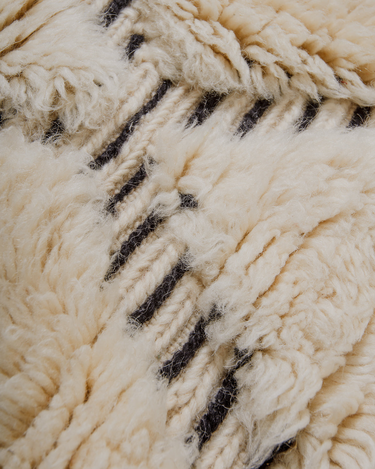 Close up of cream wool rug with black stripes in the woven design.