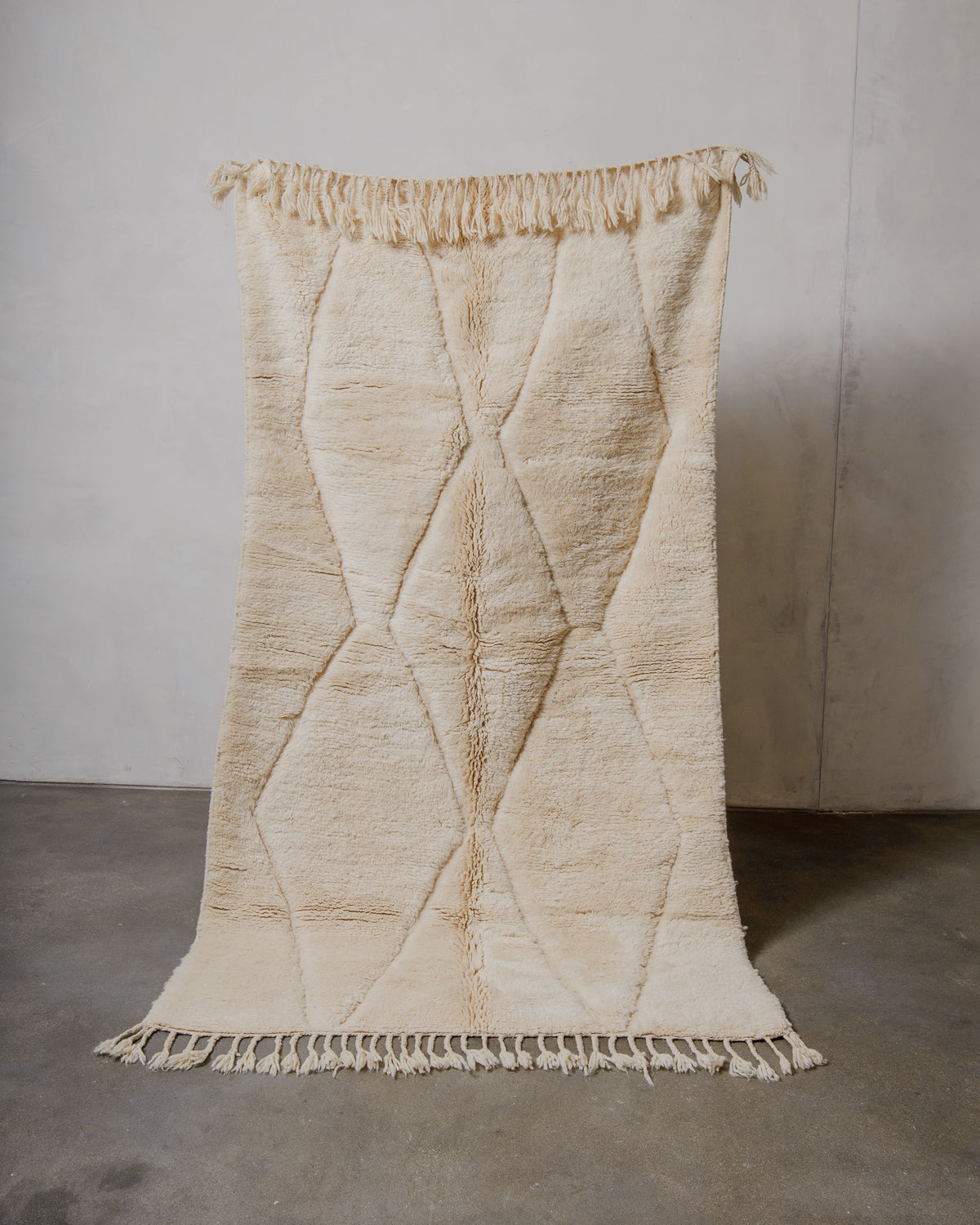 Beige textured wool rug with diamond pattern on a plain background.