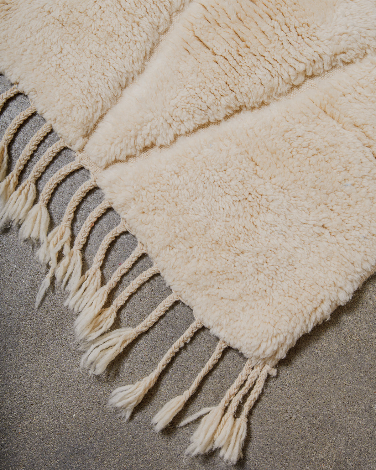 Cream wool rug with tassels on a neutral background