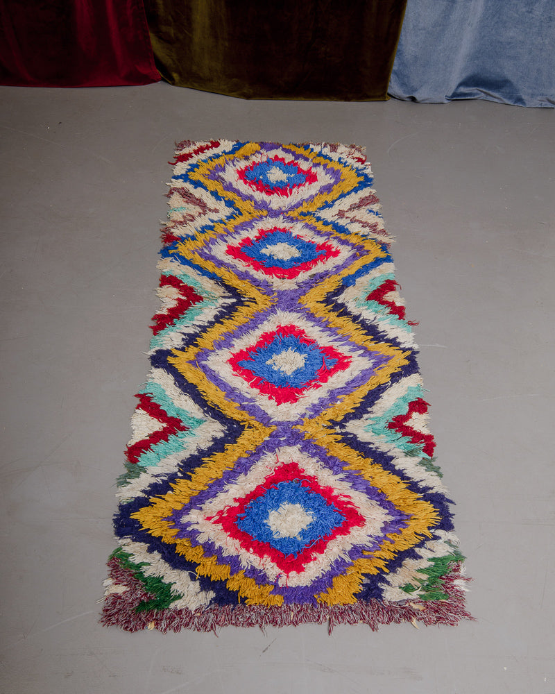Vintage Berberlin boucherouite runner rug on grey floor.