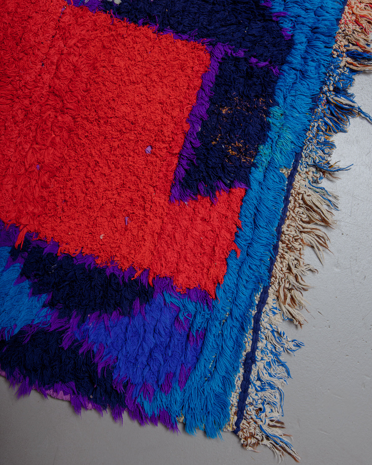 Corner of boucherouite rug with red, blue, and purple threads.