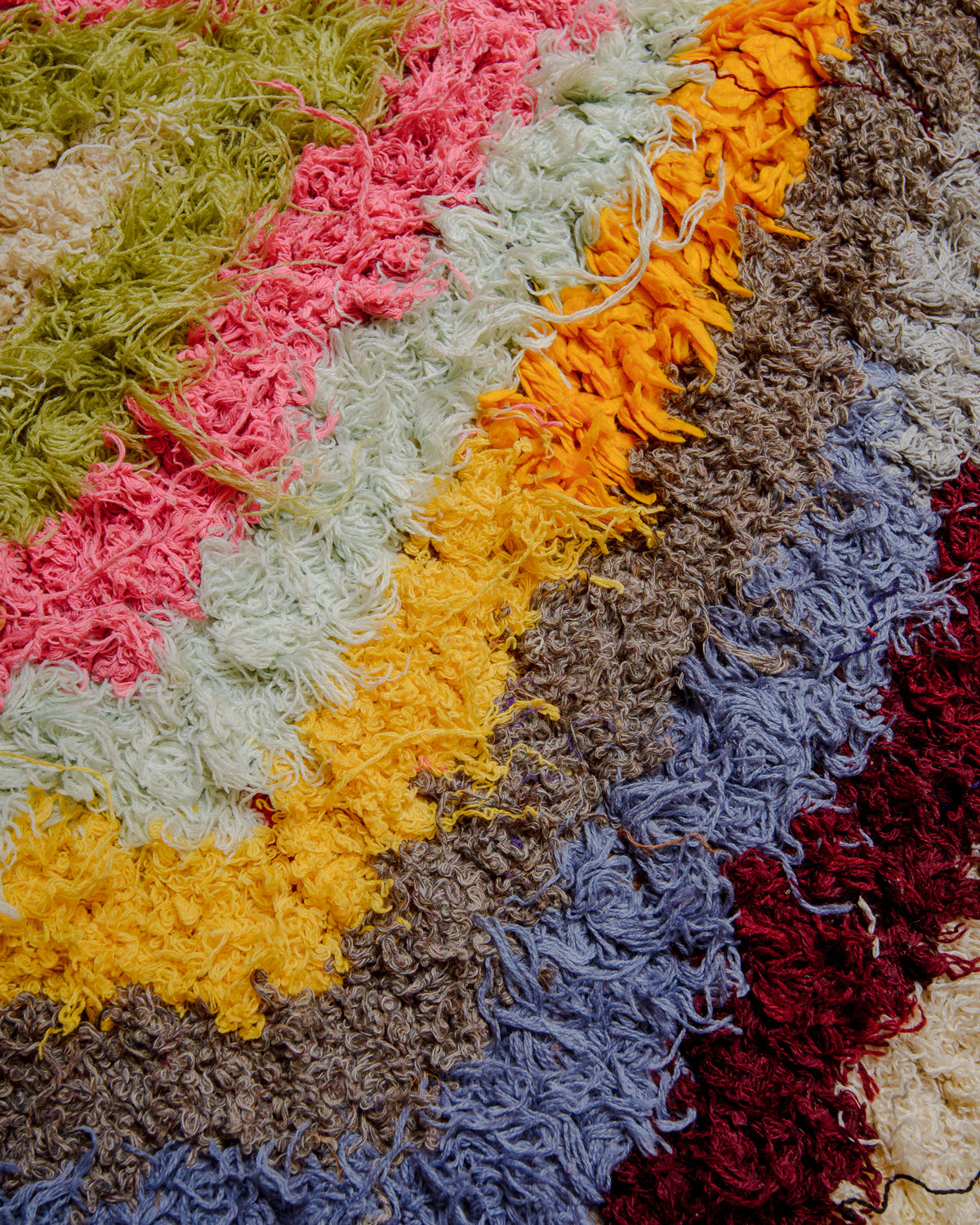 Close up of surface of Boucherouite rug in  pink, orange, yellow, kiwi, blue and red.