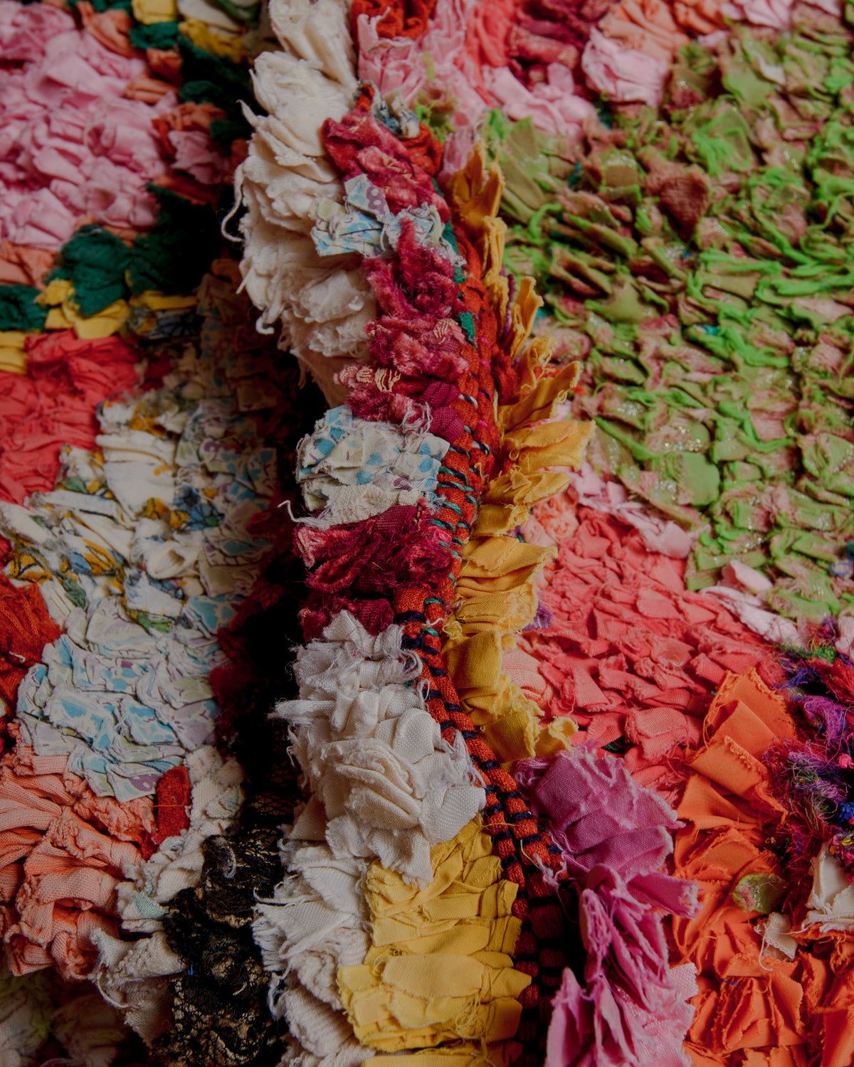 Close up of texture of Boucherouite rug in varying shades of pink, orange, red and green.