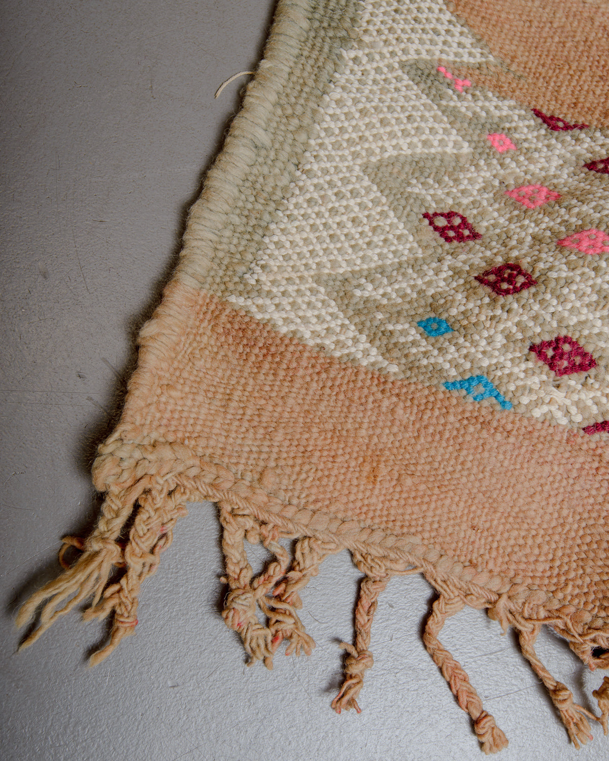 Corner of vintage kelim rug with tassels.