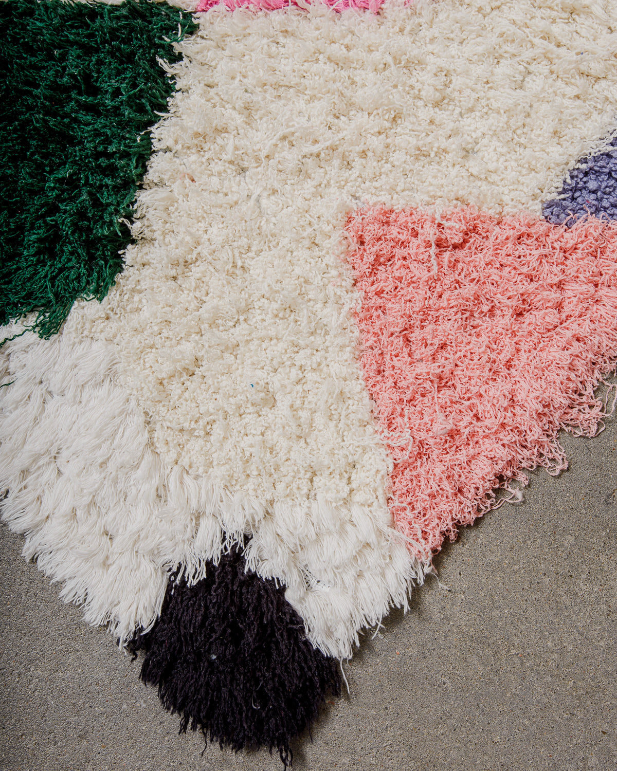 Multicoloured textured rug with geometric pattern on a neutral background.