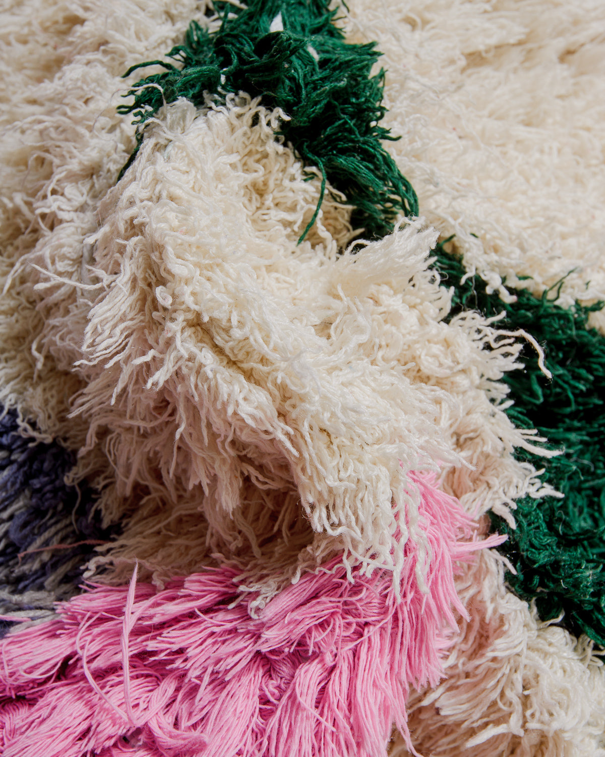 Close-up of a textured fabric rug with pink, green, and cream colours.