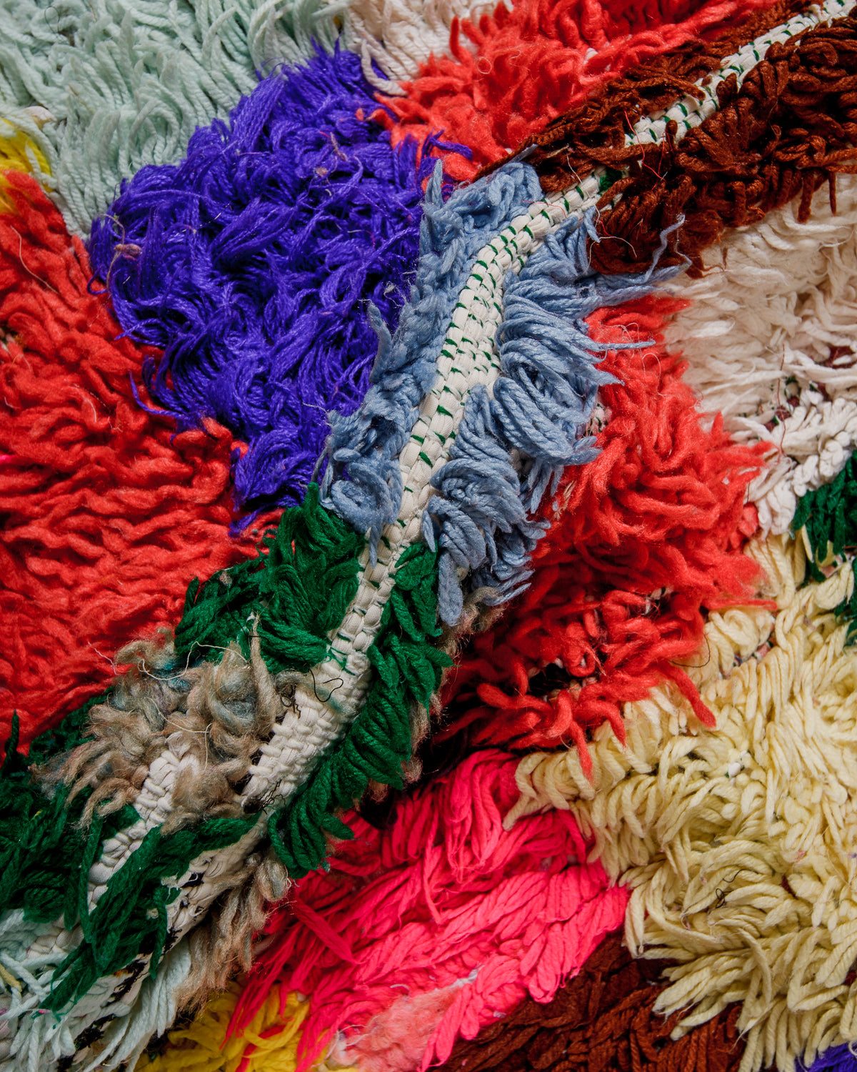 Close-up of a colourful textured fabric rug with various colours including red, blue, green, and purple.