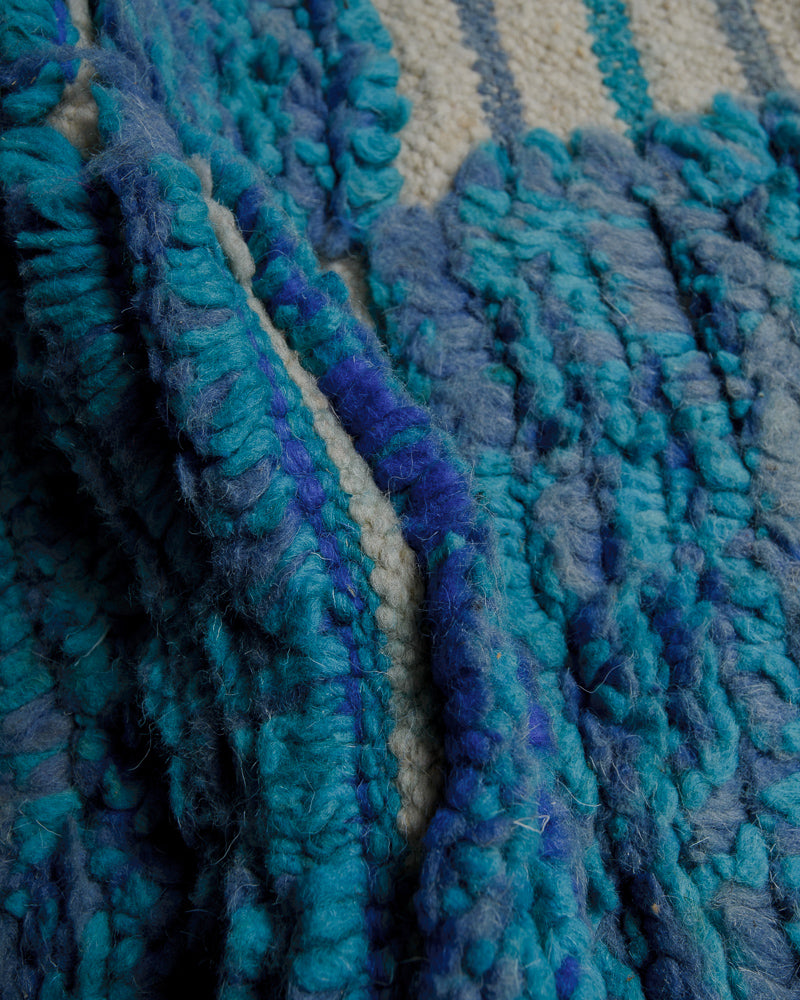 Close up of wool rug made of different shades of blue and natural wool colour. 