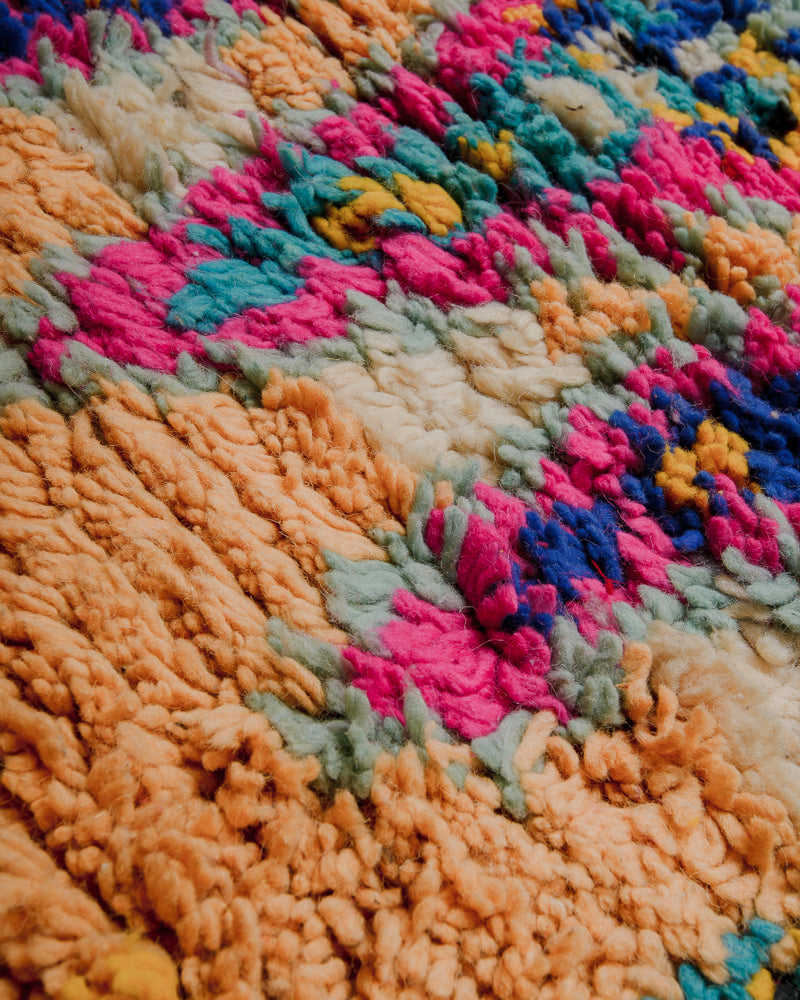 Close up of wool rug made of different shades of pink, blue , yellow, orange